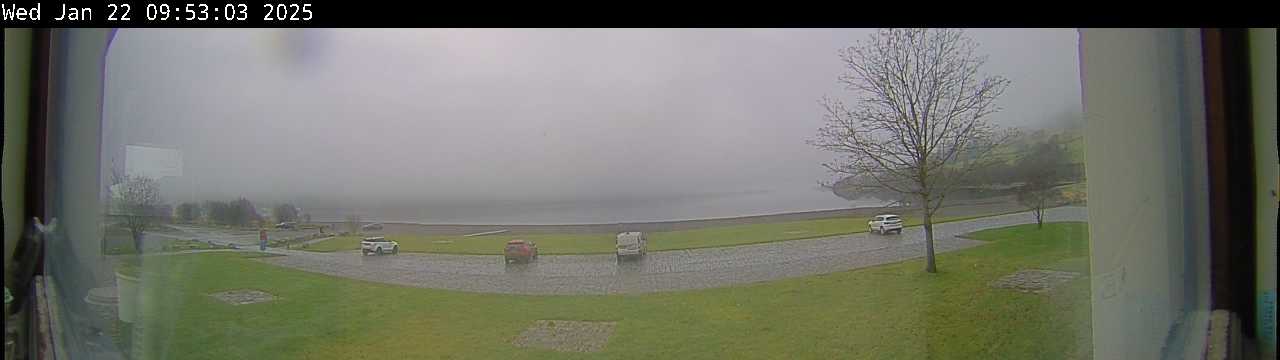 Live webcam stream showing Llyn Tegid, with the water extending into the background, surrounded by mountains and grasslands, and real-time weather changes visible.