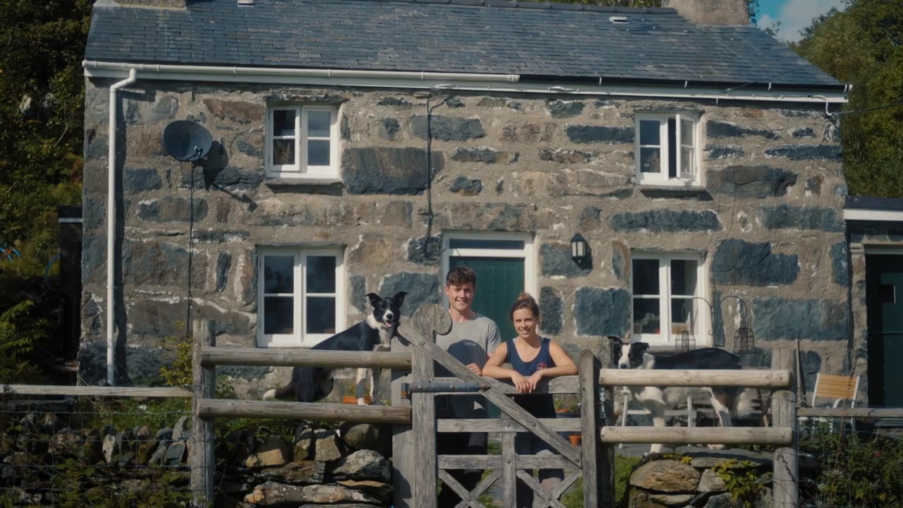 Farmers and sheepdog standing outside their house