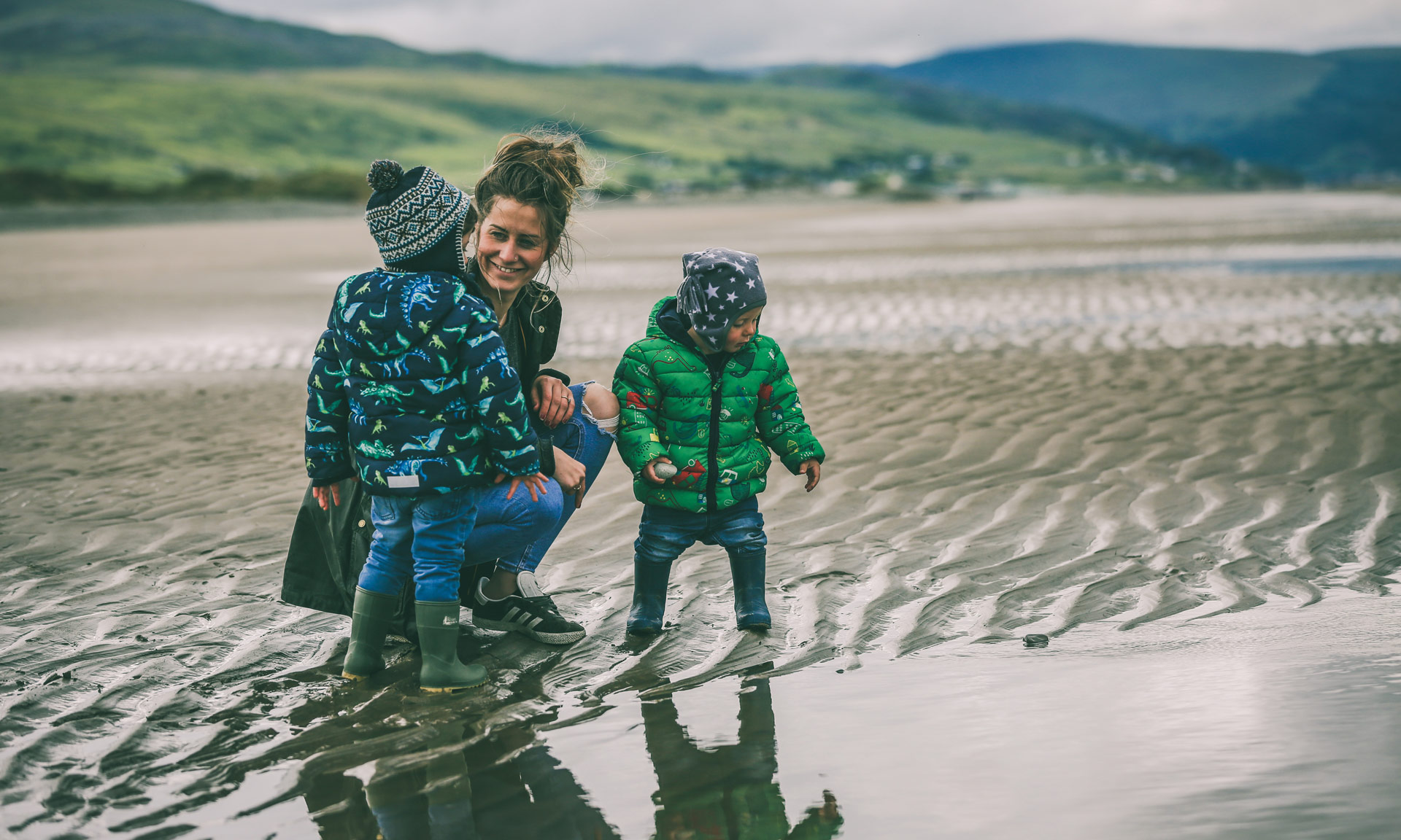 A family enjoy Benar beach with the mountains in the background