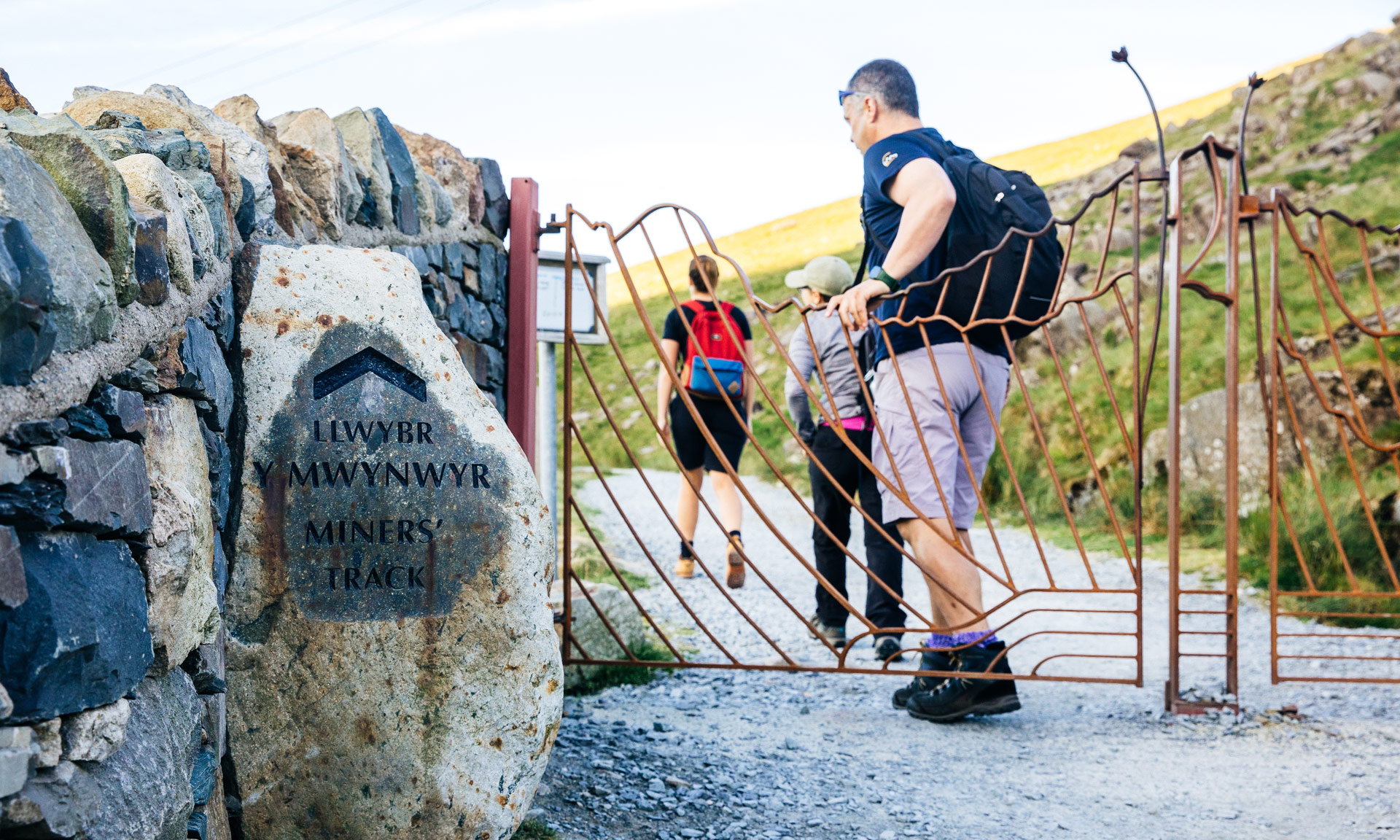 A hiker passes a sign marking the start of the Miner's path