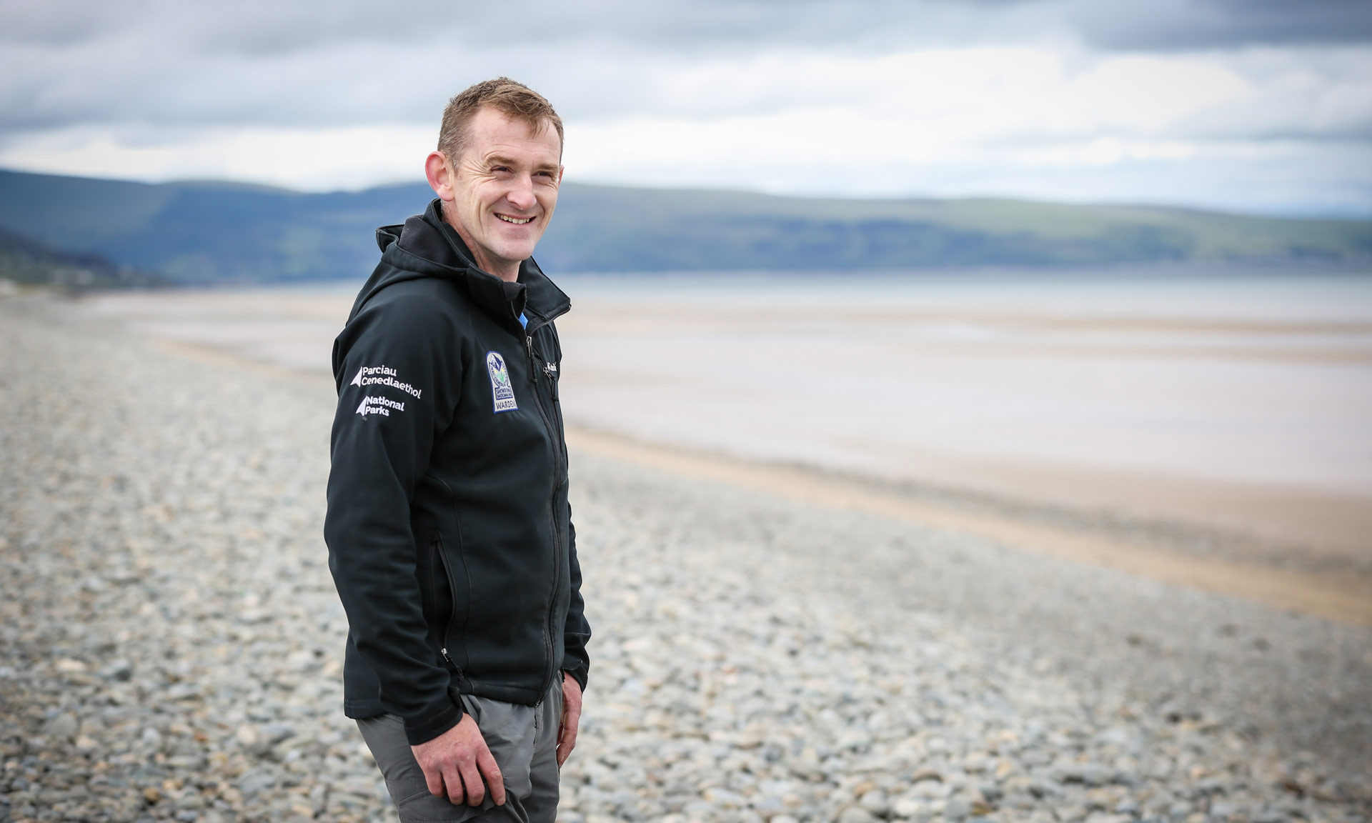 Eryri National Park warden on the coast of Eryri smiling at the camera