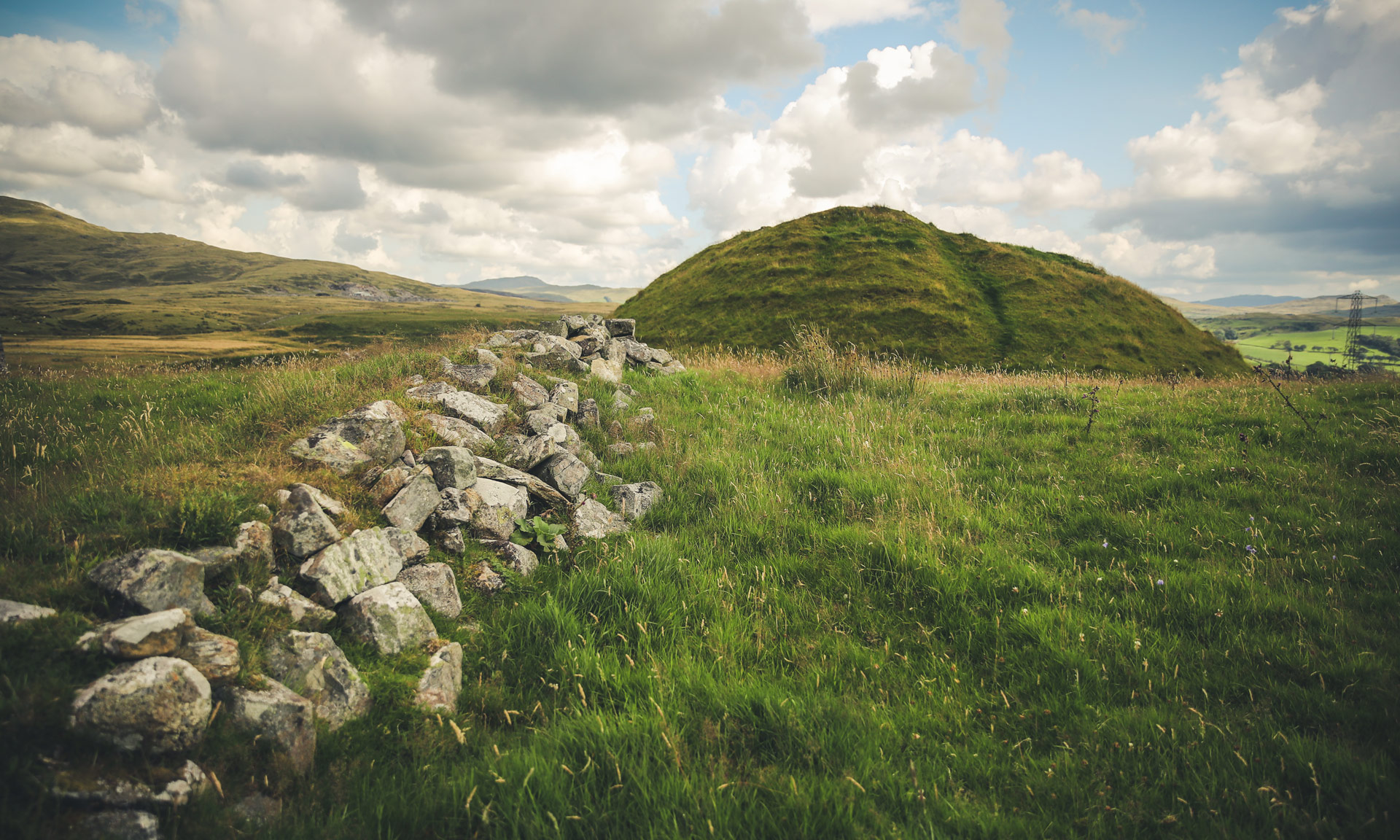 Remains of the old Roman fort Tomen y Mur with the mound in the distance