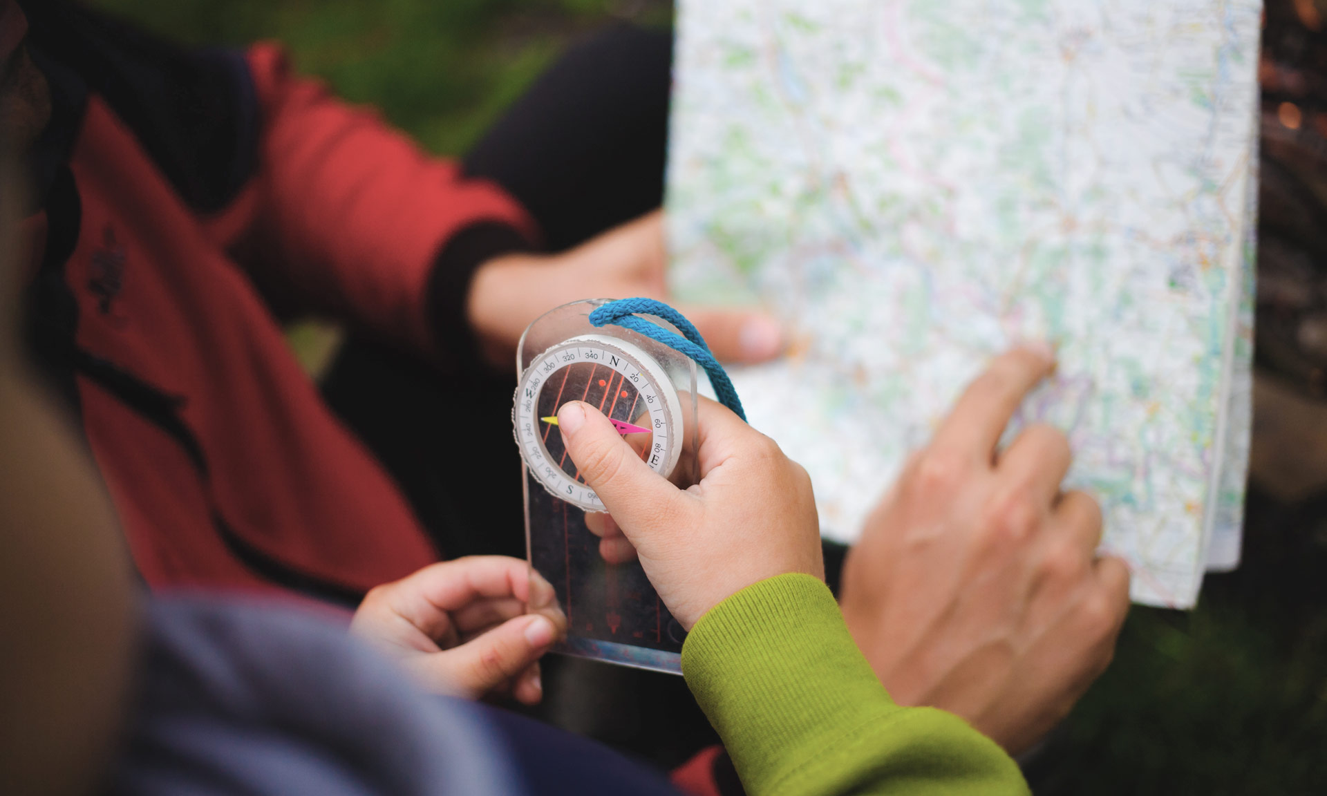 A person holding a map and a child holding a compass