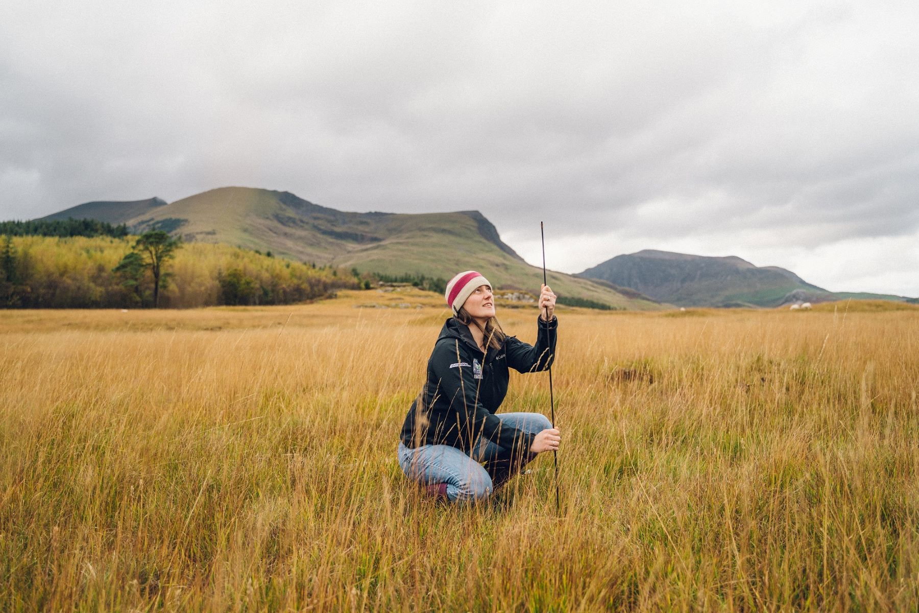 A National Park officer measures peatland in an open, vast field.