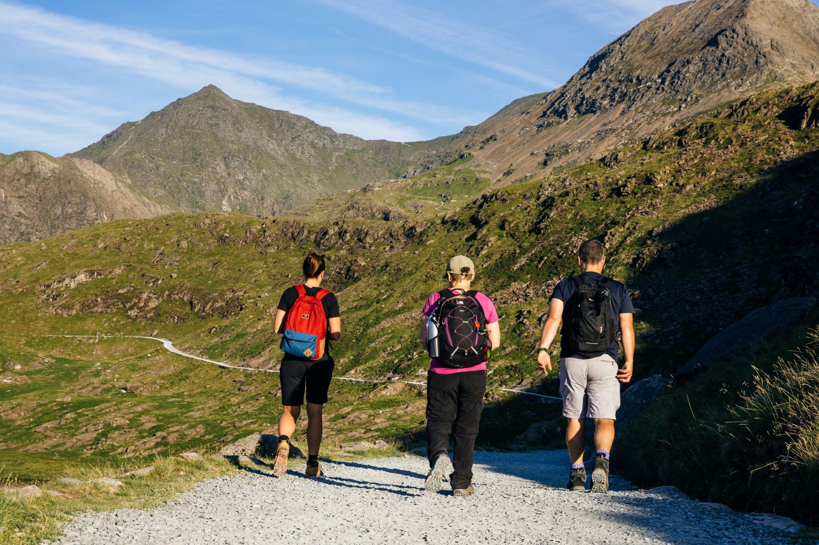 Three hikers on the Miners Track with Yr Wyddfa's summit in the distance.