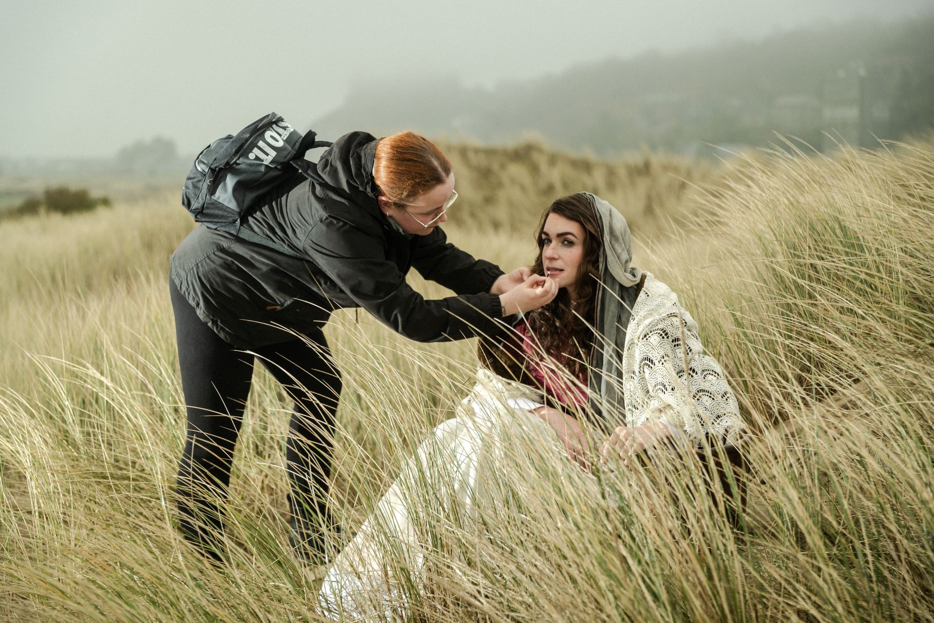 A make-up artist gives finishing touches to a model's make up on location on a promotional shoot.